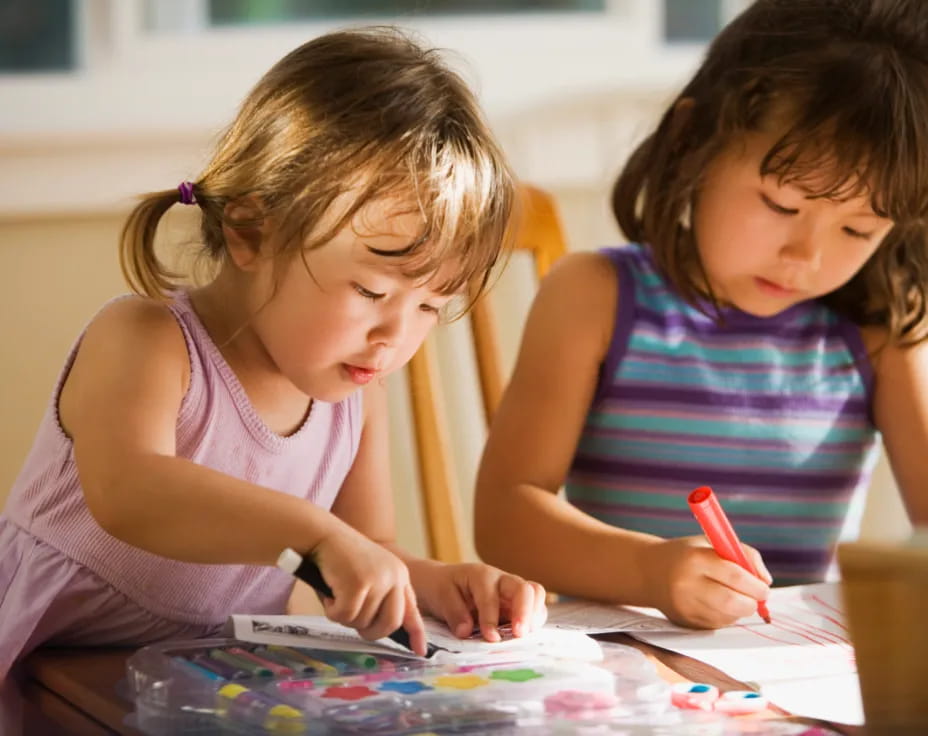 a young girl and a young girl coloring on a paper