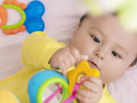 a baby holding a yellow toy