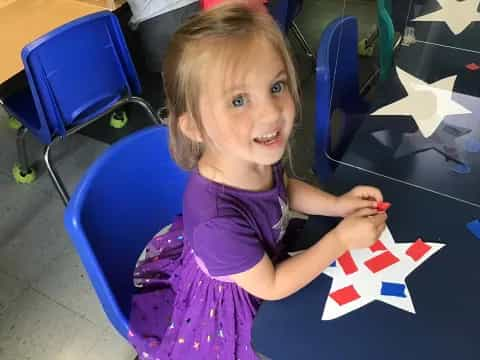 a girl sitting at a table with a kite