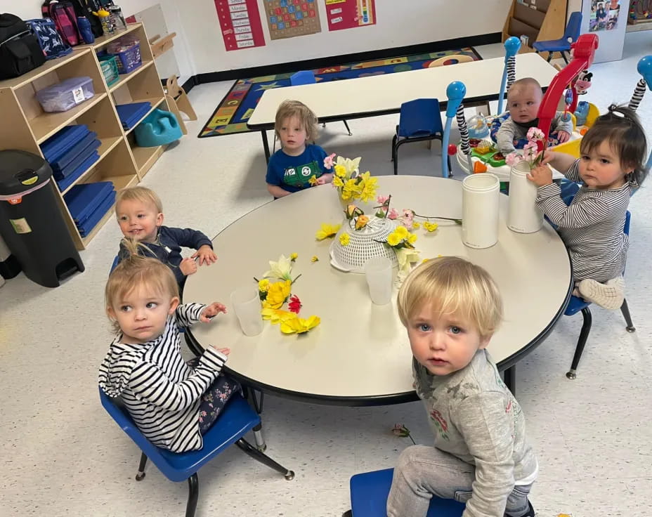 a group of children sitting around a table with flowers