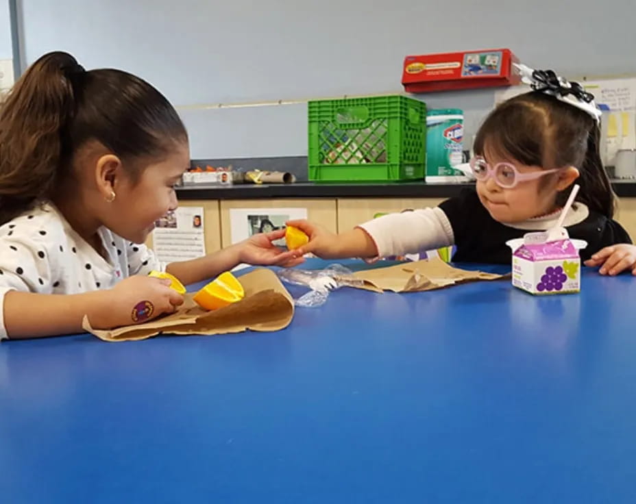 a couple of children sitting at a table with a blue table and a blue chair with a blue