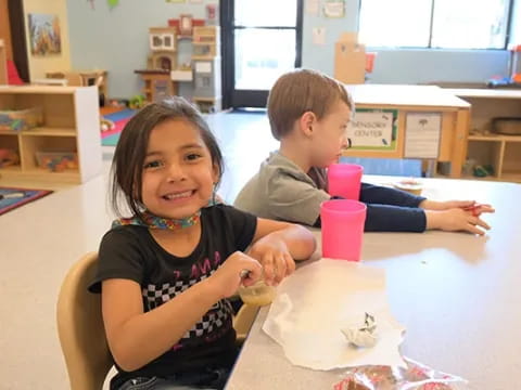 a boy and girl sitting at a table with cups