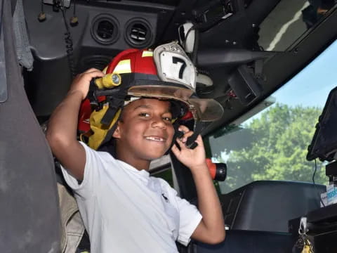 a boy wearing a helmet and sitting in a car