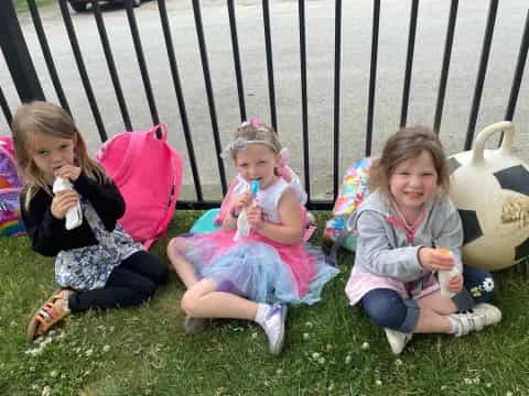 a group of girls sitting on the grass eating ice cream