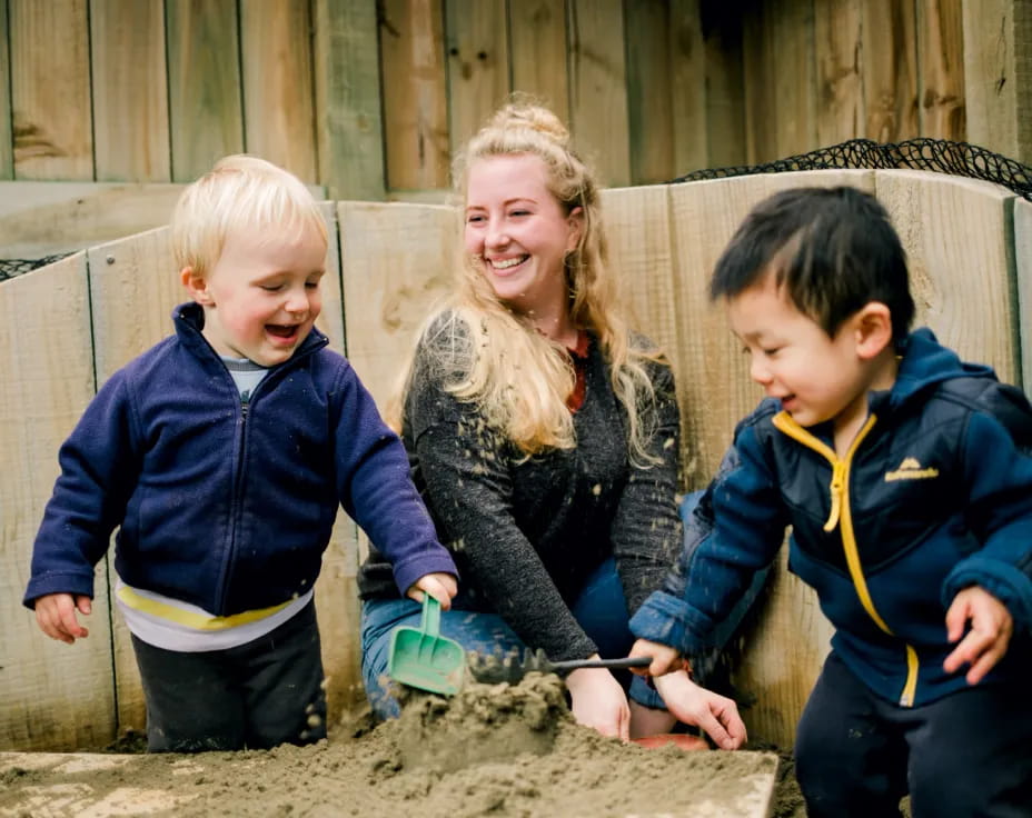 a person and two children playing in the sand