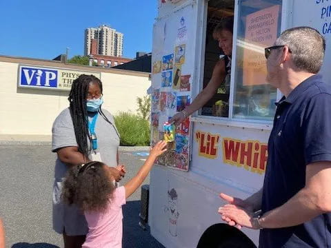 a man and a couple of girls getting food from a food truck
