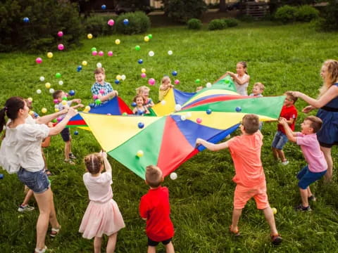 a group of children playing with a flag in a grassy area