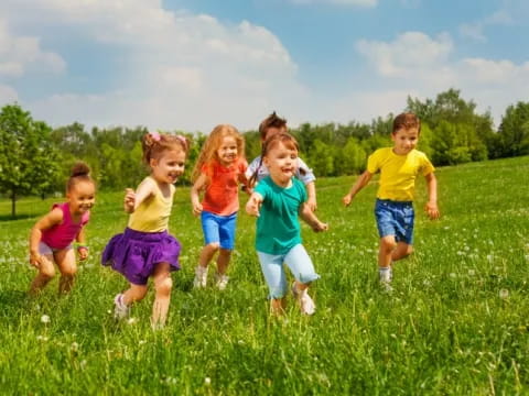 a group of children running in a grassy field