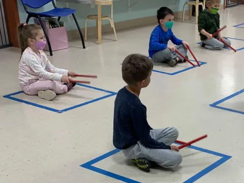 a group of children playing with toy swords on a blue floor