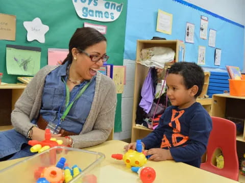 a person and a boy playing with toys in a classroom