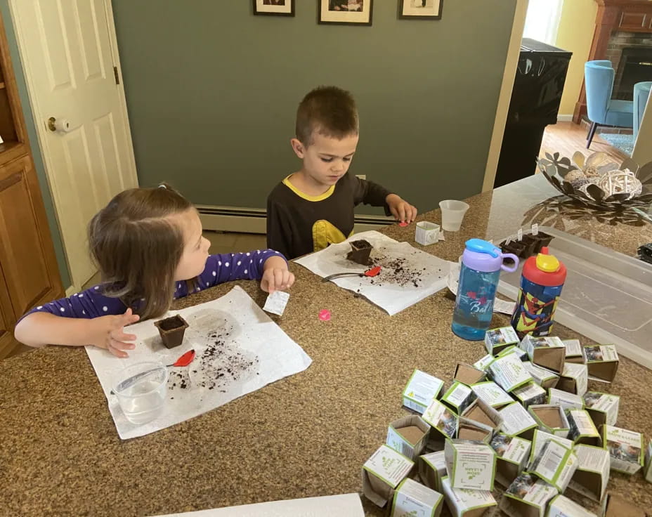 a couple of kids sitting at a table with a cake and some food