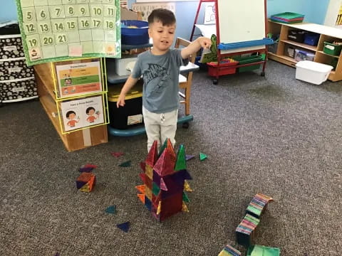 a boy standing in a room with toys and a table