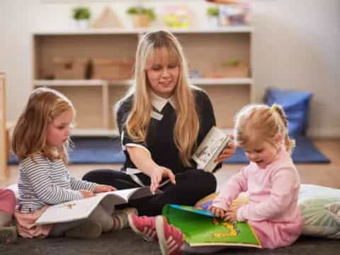 a woman reading a book to a few children