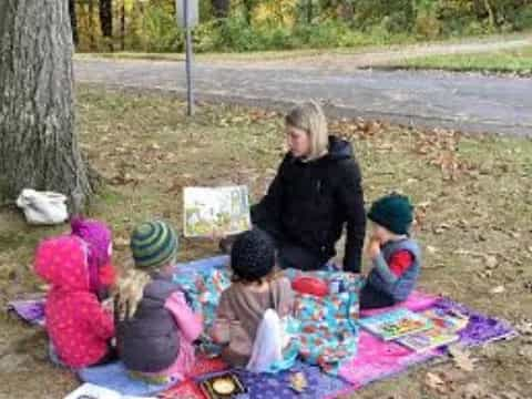 a person and several children sitting on the ground