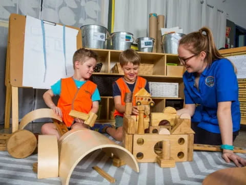 a person and two boys playing with wooden blocks