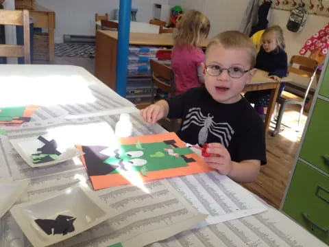 a boy sitting at a table with a book and a group of children