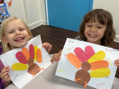 a couple of children holding up drawings