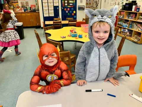 a couple of children sitting at a table with a toy