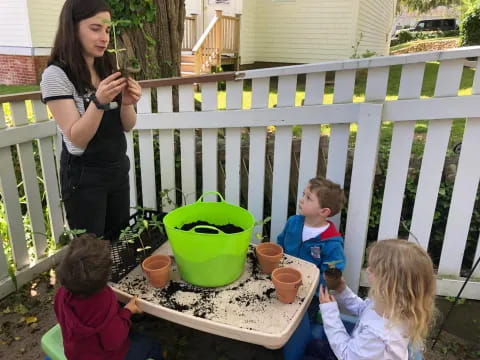 a woman and children sitting on a deck with potted plants