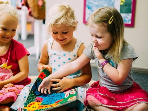 a group of children sitting on the floor looking at a book