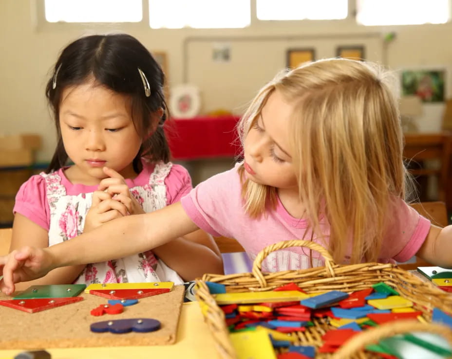 a couple of young girls playing with toys in a classroom