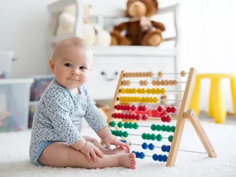 a baby sitting on the floor next to a toy house