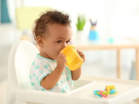 a baby drinking from a yellow cup