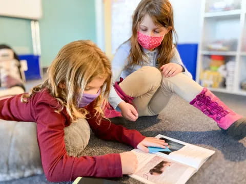 a young girl helping a young girl with a book