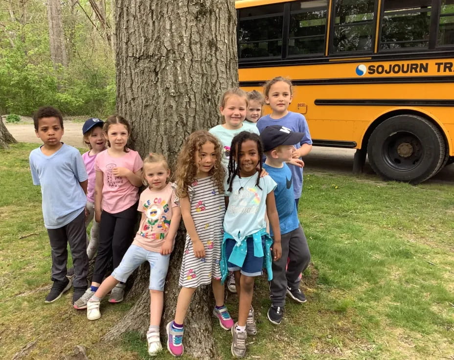 a group of children posing for a photo in front of a tree