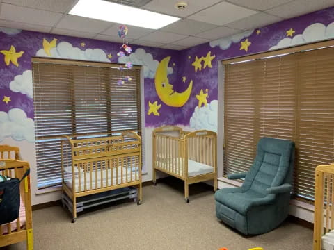a room with a crib and chairs