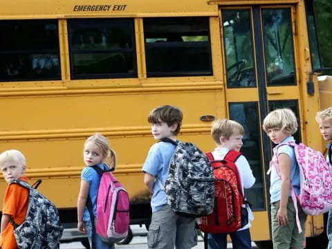 a group of children standing in front of a school bus