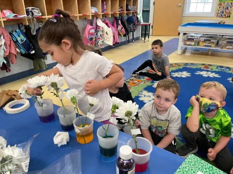 a person and two children sitting at a table with flowers