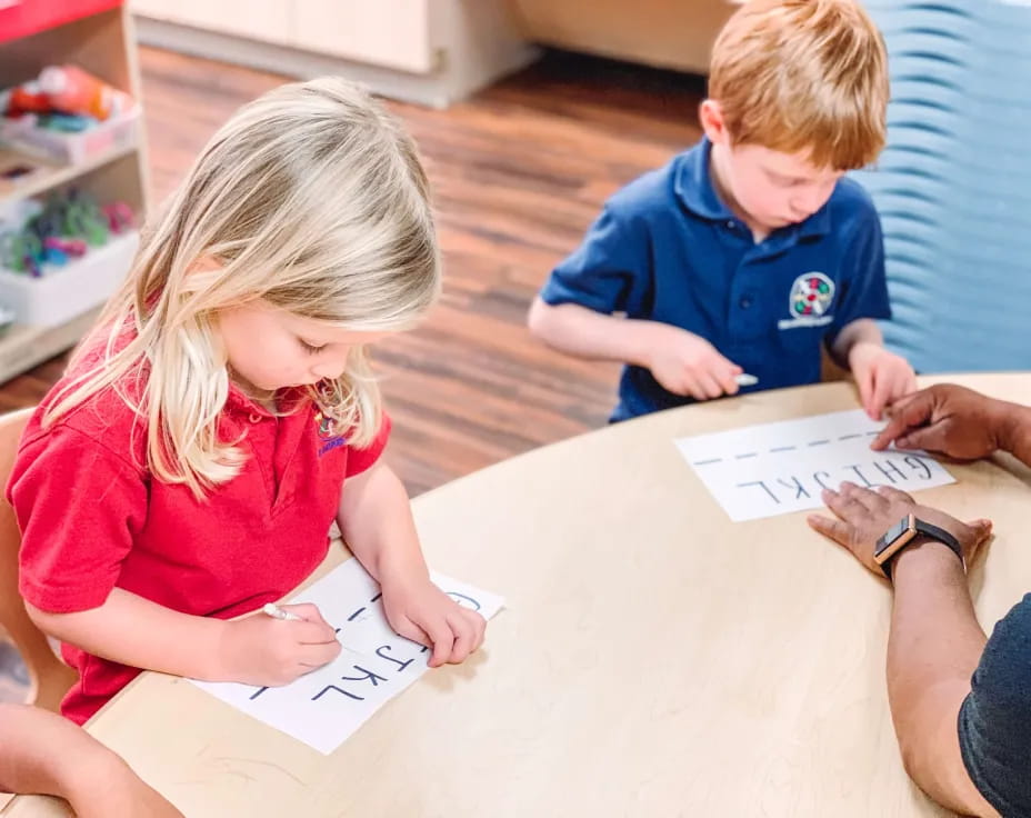 children sitting at a table writing on paper