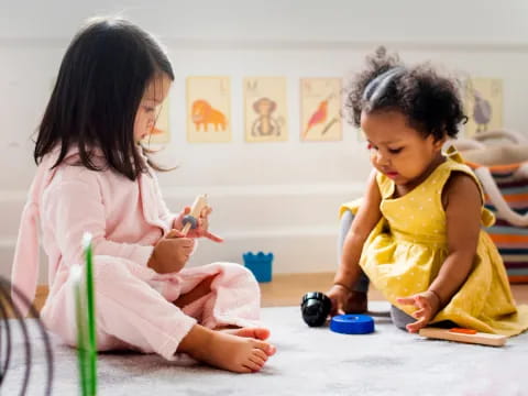 a couple of young girls playing with toys on the floor