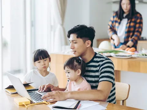 a person and a couple of children looking at a laptop