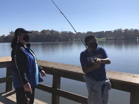a person holding a fishing pole next to a person holding a fishing pole