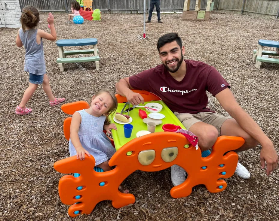 a person and two children playing in a sandbox