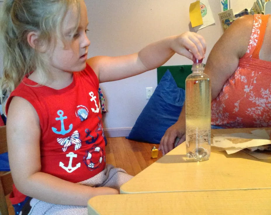 a young girl painting a bottle