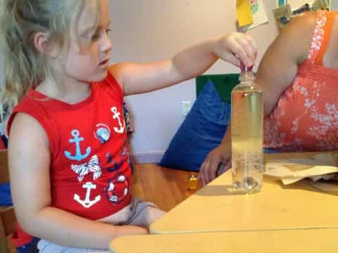 a young girl painting a bottle