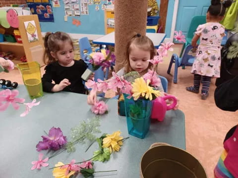 a couple of young girls sitting at a table with flowers