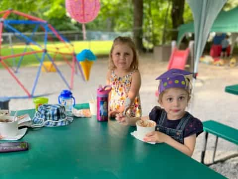 a couple of girls sitting at a table with food and drinks