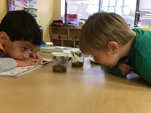 a couple of boys looking at a book on a table