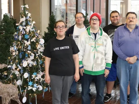 a group of people posing for a photo next to a christmas tree
