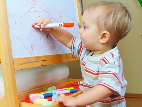 a baby drawing on a white board
