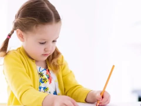 a little girl holding a pencil