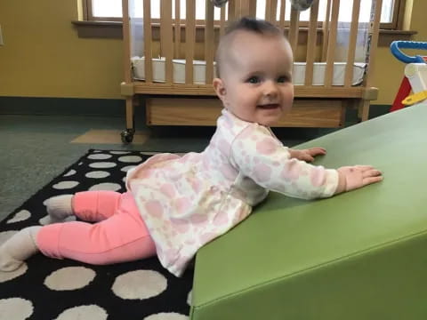 a baby sitting on a green slide
