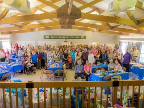 a group of people standing in a room with tables and chairs