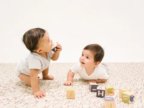 a couple of babies playing with blocks