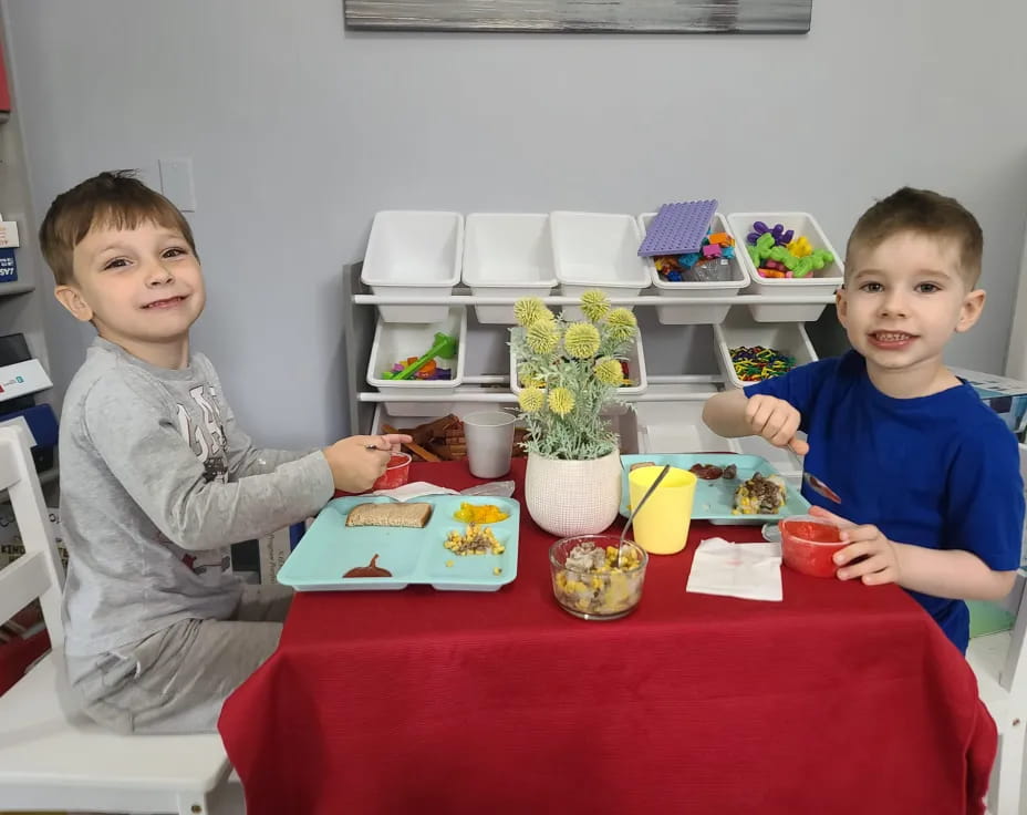 a person and a boy sitting at a table with food and drinks