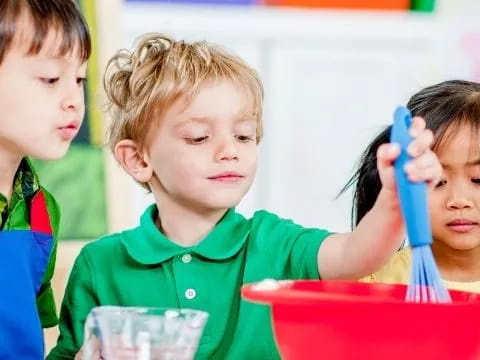 a group of children holding a blue spoon